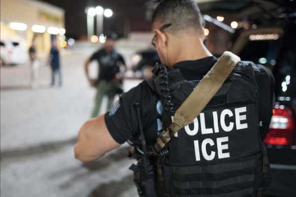 ICE agent seen from rear.