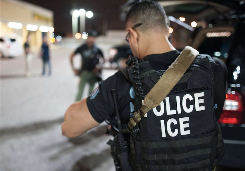 ICE agent seen from rear.